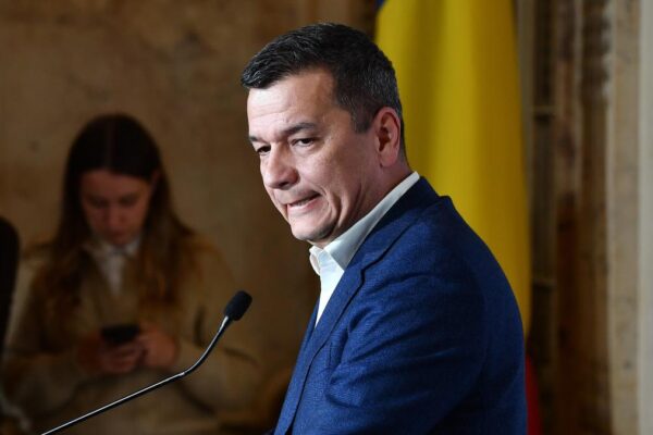 Bărbat în costum vorbind la un pupitru oficial