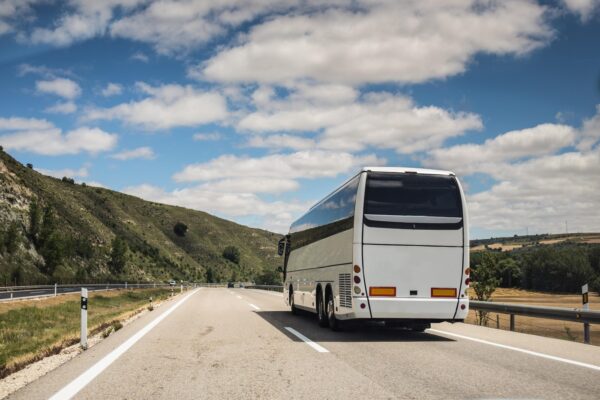 Autocar alb pe autostradă prin peisaj deluros