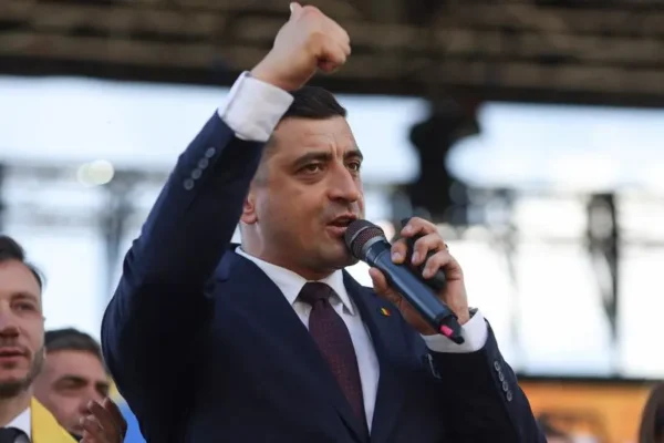 Bărbat în costum ținând discurs cu pumnul ridicat