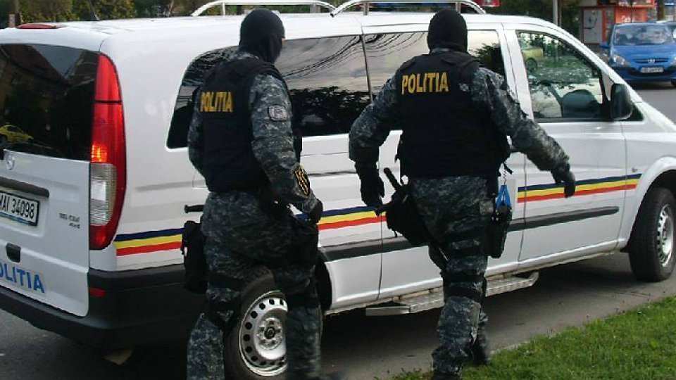 Doi polițiști mascați lângă dubă Poliția